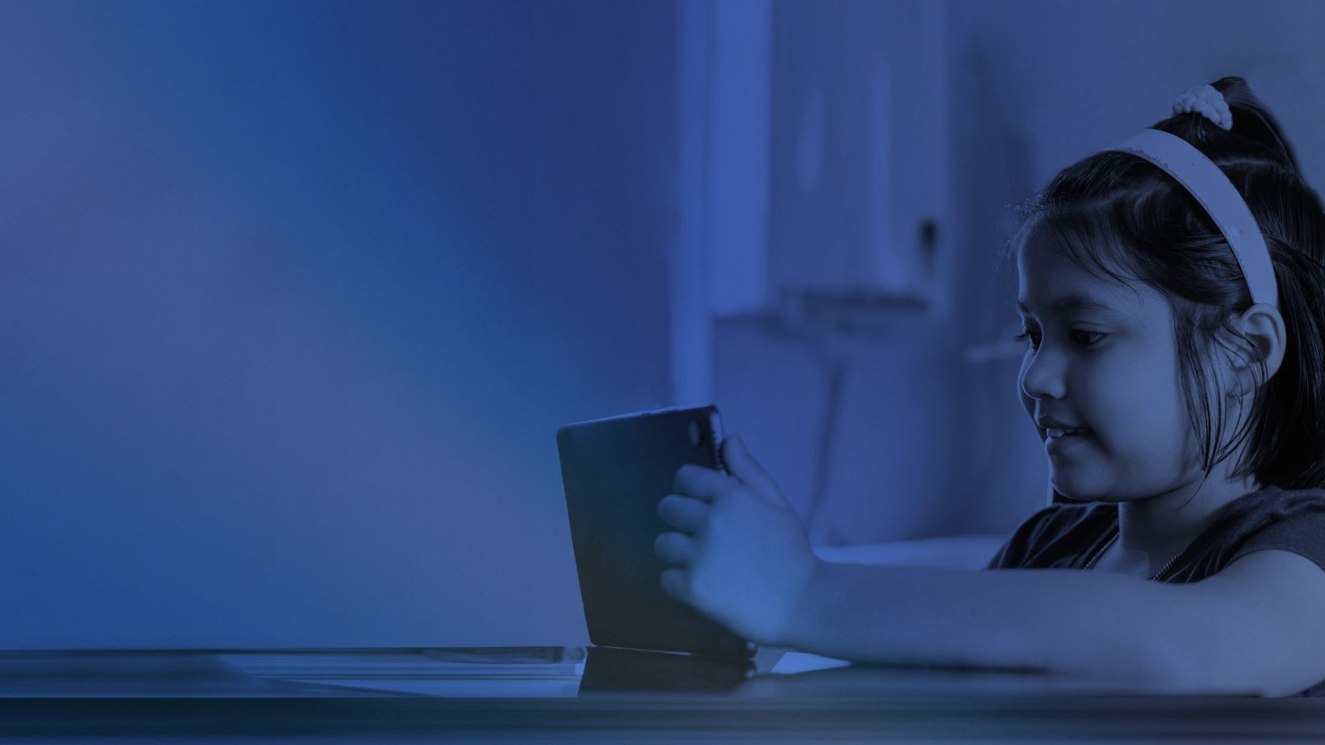 Niña estudiando en una clase virtual con una tableta desde su casa